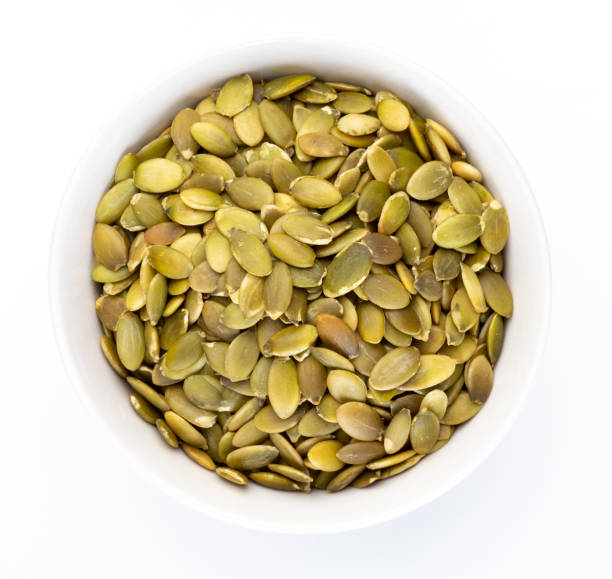 istock Pumpkin seeds (peeled seeds) in white bowl (Various nuts collection). Isolated on white background. 1074869542