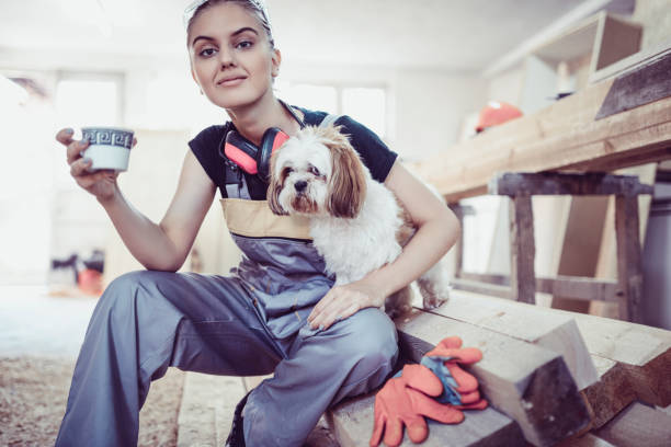 istock Cute Female Carpenter Posing With His Dog While Drinking Coffee On a Job Break 1074873460
