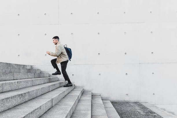 Young man running up steps in urban setting Young man running up steps in urban setting way to school stock pictures, royalty-free photos & images