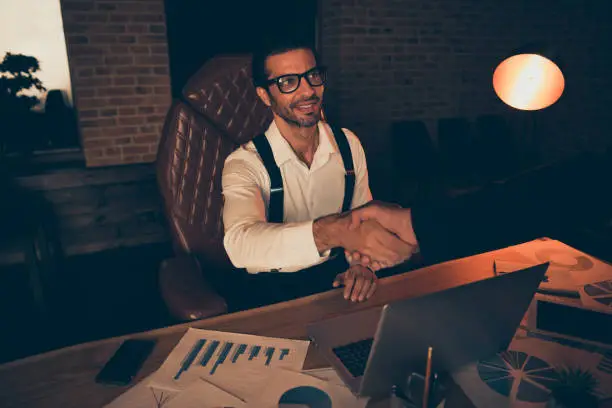 Trendy style stylish formal wear shirt suspender eyeglasses spectacles billionaire millionaire sit in chair inside loft interior notebook graph on table shake hand after signing document contract