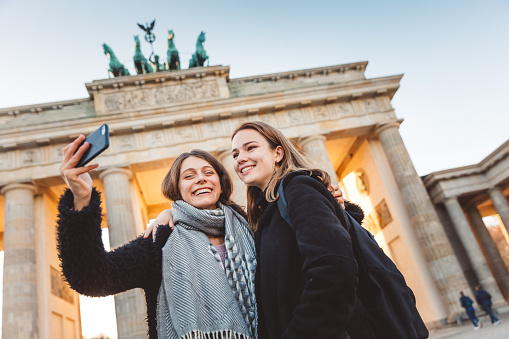 Smiling young friends taking selfie, Berlin, Brandenburg Gate\nBerlin, Germany