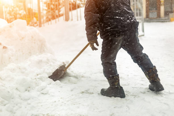 istock Man removing snow from sidewalk after heavy snowfall. Snowstorm and blizzard aftermath in winter. Slippery walkaway prevention 1074881616