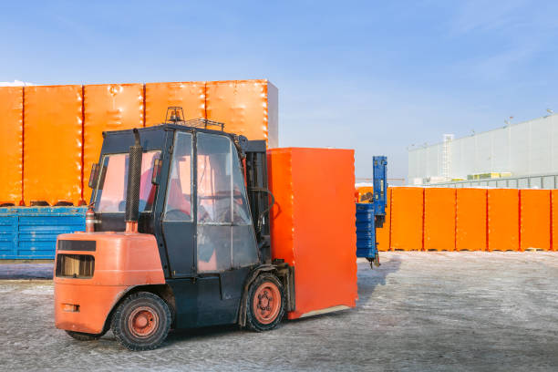 istock Forklift unloading truck semi trailer with wrapped cardboard boxes outdoors. openair warehouse works background 1074887856
