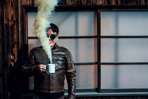 Mid adult man holding a smoldering coffee cup with smoke pouring out