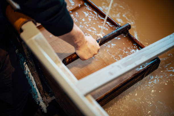Mid adult Japanese man making paper using traditional methods