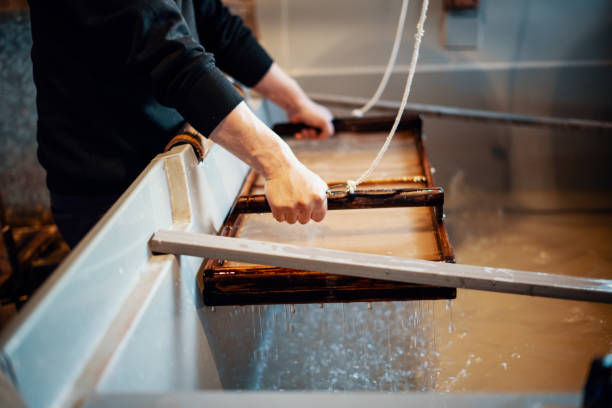 istock Mid adult Japanese man making paper using traditional methods 1074887904