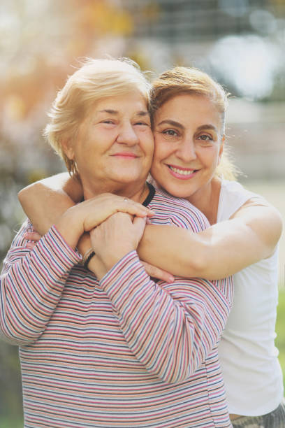 Loving adult daughter embracing cheerful senior mother stock photo