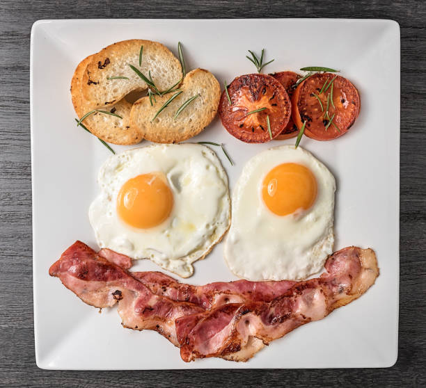 The perfect breakfast with fried eggs, bacon, tomatoes and bread stock photo