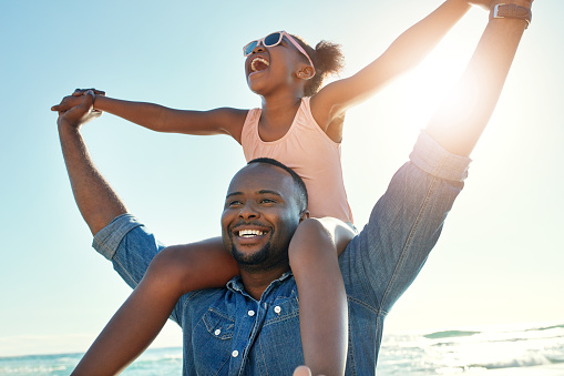 Shot of an adorable little girl having fun with her father  on the beach