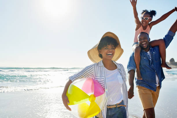 The greatest pleasures of life Shot of an adorable little girl going for a walk with her parents on the beach beach play stock pictures, royalty-free photos & images