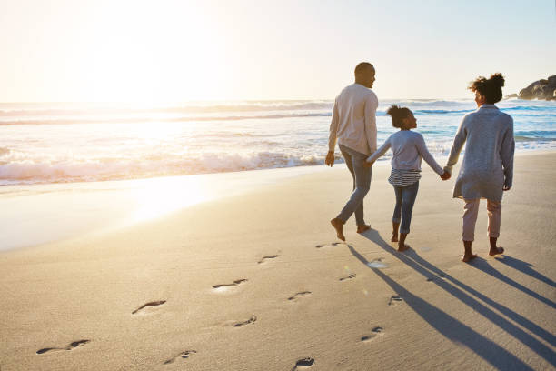 passeggiate al tramonto sulla spiaggia con la famiglia - family beach cheerful happiness foto e immagini stock
