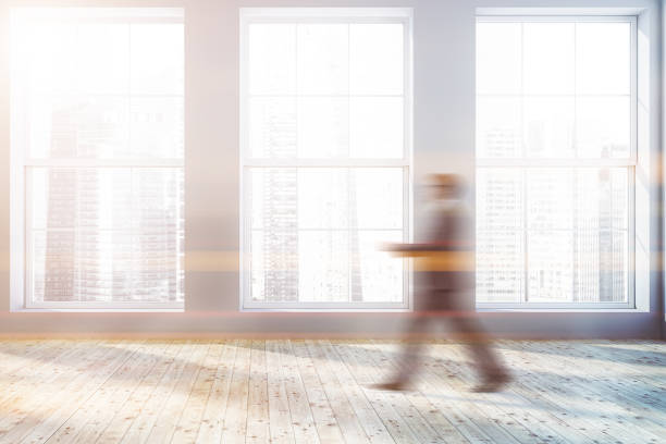 istock Man walking in gray room with windows 1074900930
