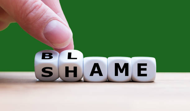 hand turns dices and changes the word "shame" to "blame" - culpa imagens e fotografias de stock