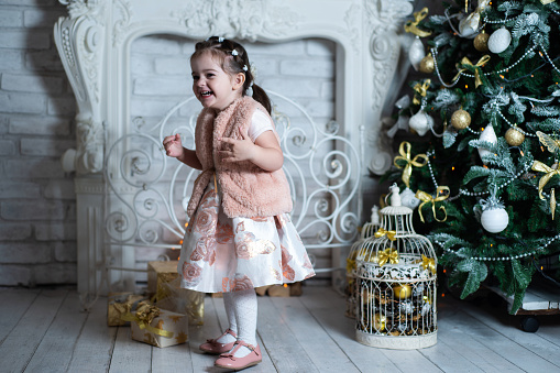 Happy and joyful little girl having fun near the Christmas tree.