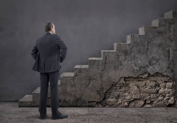 Rear view of businessman standing on wooden floor and concrete staircase with damaged plaster.