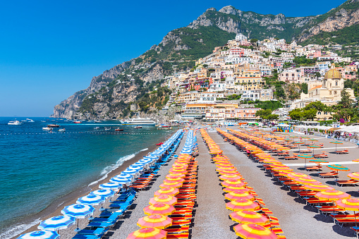 View of famous rows of blue and orange beach umbrellas on Positano Beach, Amalfi Coast, Italy.