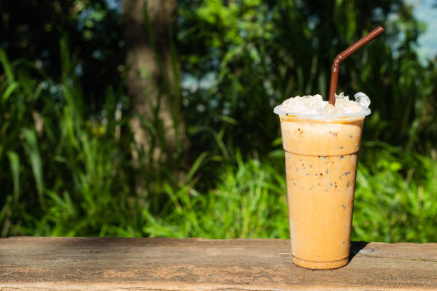 istock Iced coffee and a background of green trees. 1074929542