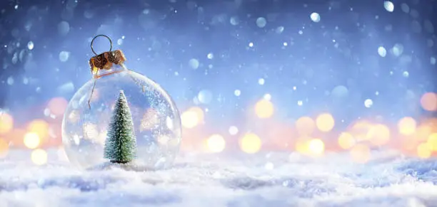 Photo of Snow Ball With Christmas Tree In It And Lights On Winter Background
