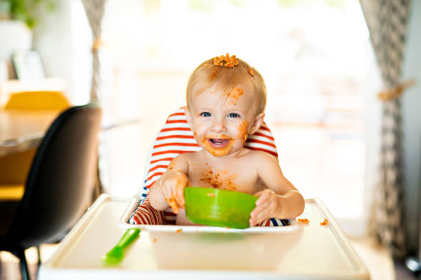istock Little baby eating spaghetti dinner and making a mess 1074943130