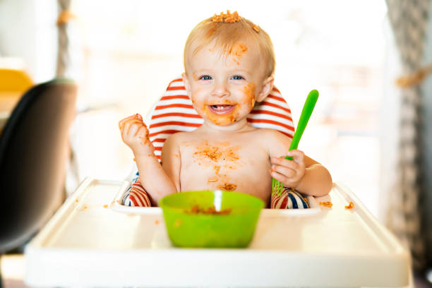istock Little baby eating spaghetti dinner and making a mess 1074943190