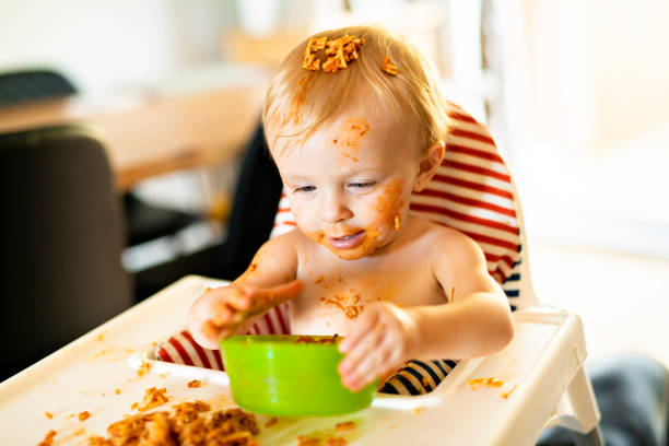 istock Little baby eating spaghetti dinner and making a mess 1074943228