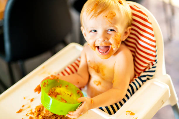 istock Little baby eating spaghetti dinner and making a mess 1074943252