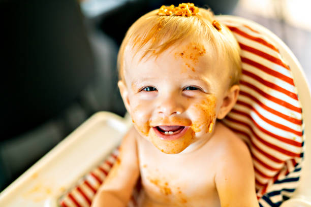 istock Little baby eating spaghetti dinner and making a mess 1074943288