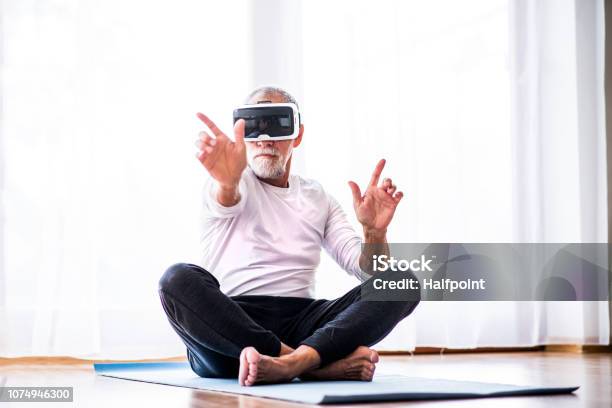 Senior Man With Vr Goggles Doing Exercise At Home Stock Photo - Download Image Now - Virtual Reality Simulator, Virtual Reality, Exercising