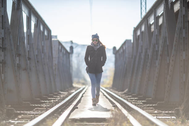 Young woman walking on the old metal railway bridge
