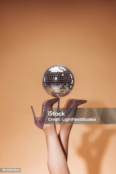 Cropped Image Of Woman Holding Shiny Disco Ball On High Heels At Party On Beige Stock Photo - Download Image Now