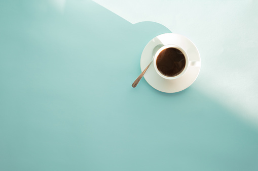 Cup of steaming coffee on seafoam green table, top view