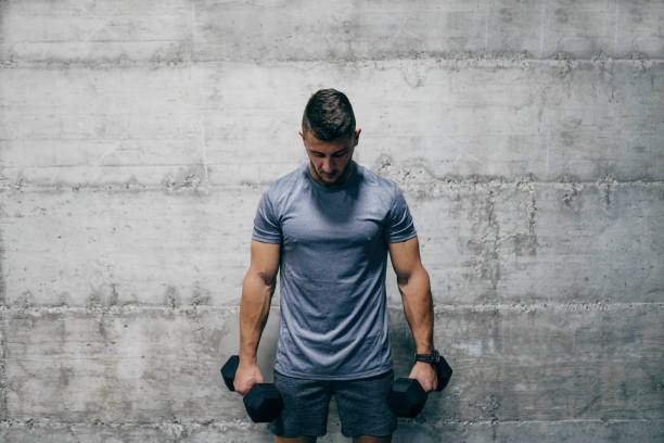 istock Man standing and holding dumbbells while looking down. Pain is temporary, quitting lasts forever. 1074962648