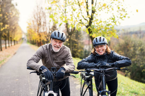 istock Active senior couple with electrobikes standing outdoors on a road in nature. 1074966732