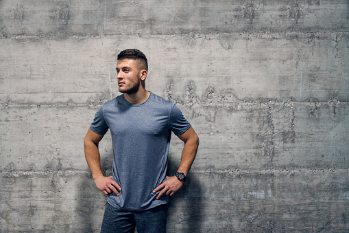Sporty Caucasian man standing in front of the wall in sportswear. Your body is a reflection of your lifestyle.