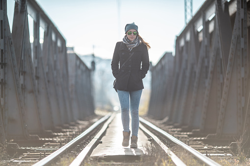 Young woman walking on the old metal railway bridge