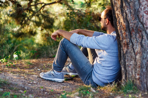 istock Single man sitting under a tree, watching his view, resting and enjoying the moment 1074969964