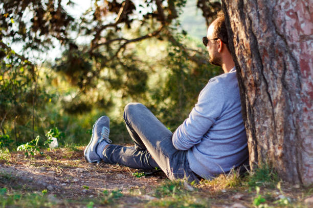 istock Single man sitting under a tree, watching his view, resting and enjoying the moment 1074970078