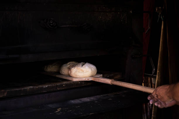 istock man putting bread dough in the wood oven 1074972164
