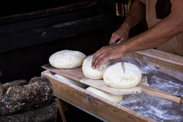 istock man putting bread dough in the wood oven 1074972214