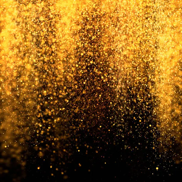 Gold sparkling dust falling over black background