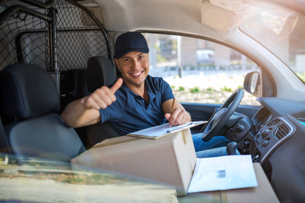 Delivery man sitting in a delivery van Smiling delivery man sitting with boxes in his van delivery person stock pictures, royalty-free photos & images