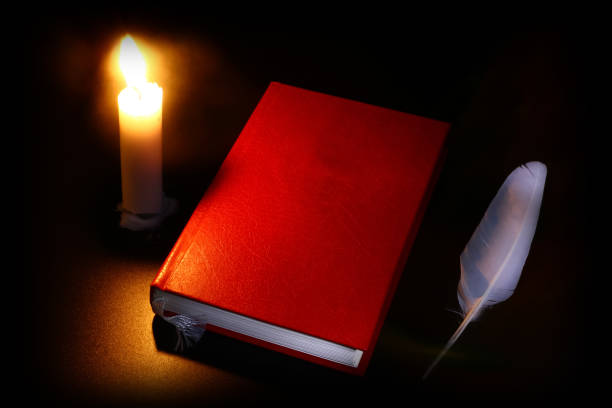 istock old book, burning candle and feather in the dark 1074976842
