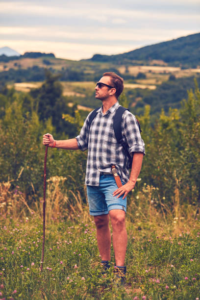 istock Hiker posing with knife on the belt in a meadow. 1074980386