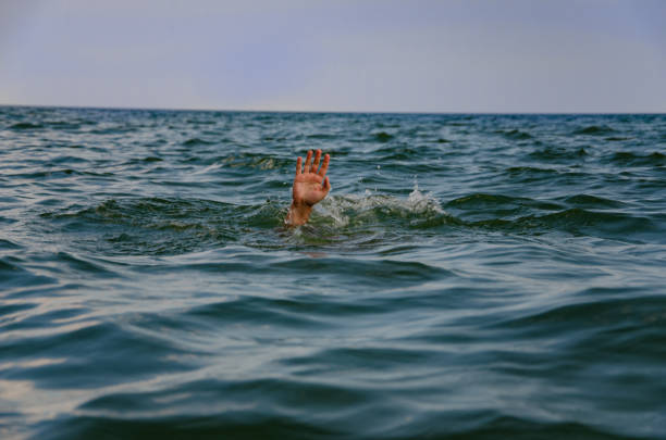 istock The hand raised above the water, against the blue sky. 1074980400