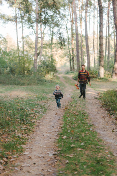 istock Man running following little boy in forest 1074982950