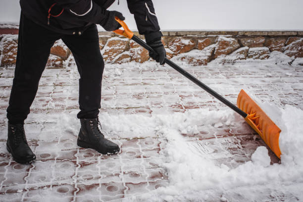 dopo una nevicata, una persona rastrella e rimuove la neve davanti alla sua casa. emergenza, nevicate. - paletta foto e immagini stock