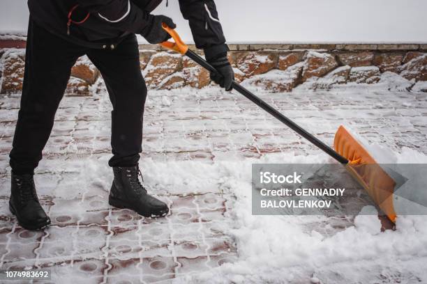 After A Snowfall A Person Rakes And Removes Snow In Front Of His House Emergency Snowfall Stock Photo - Download Image Now