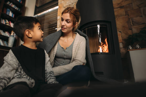 istock Young mother and son by a fireplace at home 1074984998