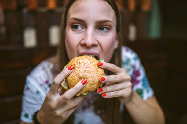 kobieta ciesząc się pyszne burger - finger licking zdjęcia i obrazy z banku zdjęć