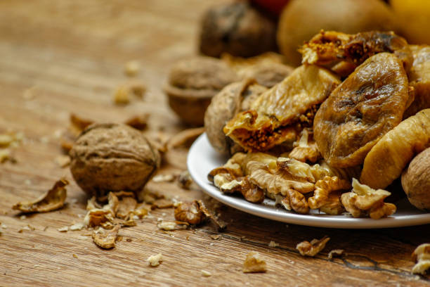 istock Dried fig and whole and cracked walnuts on white ceramic plate 1074993860